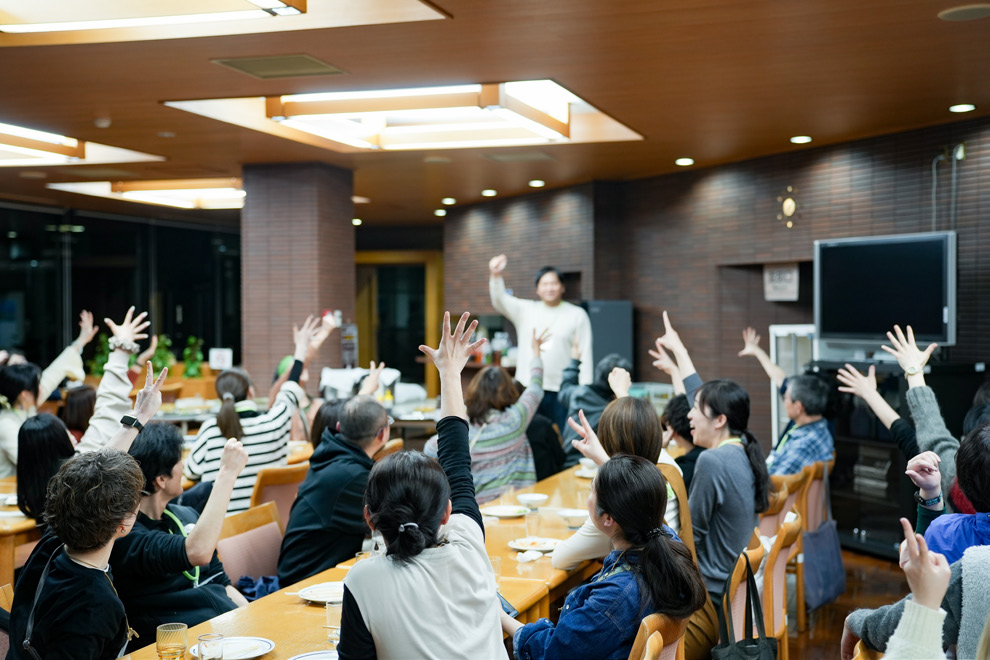 テーブルを囲み、手を挙げる参加者たち