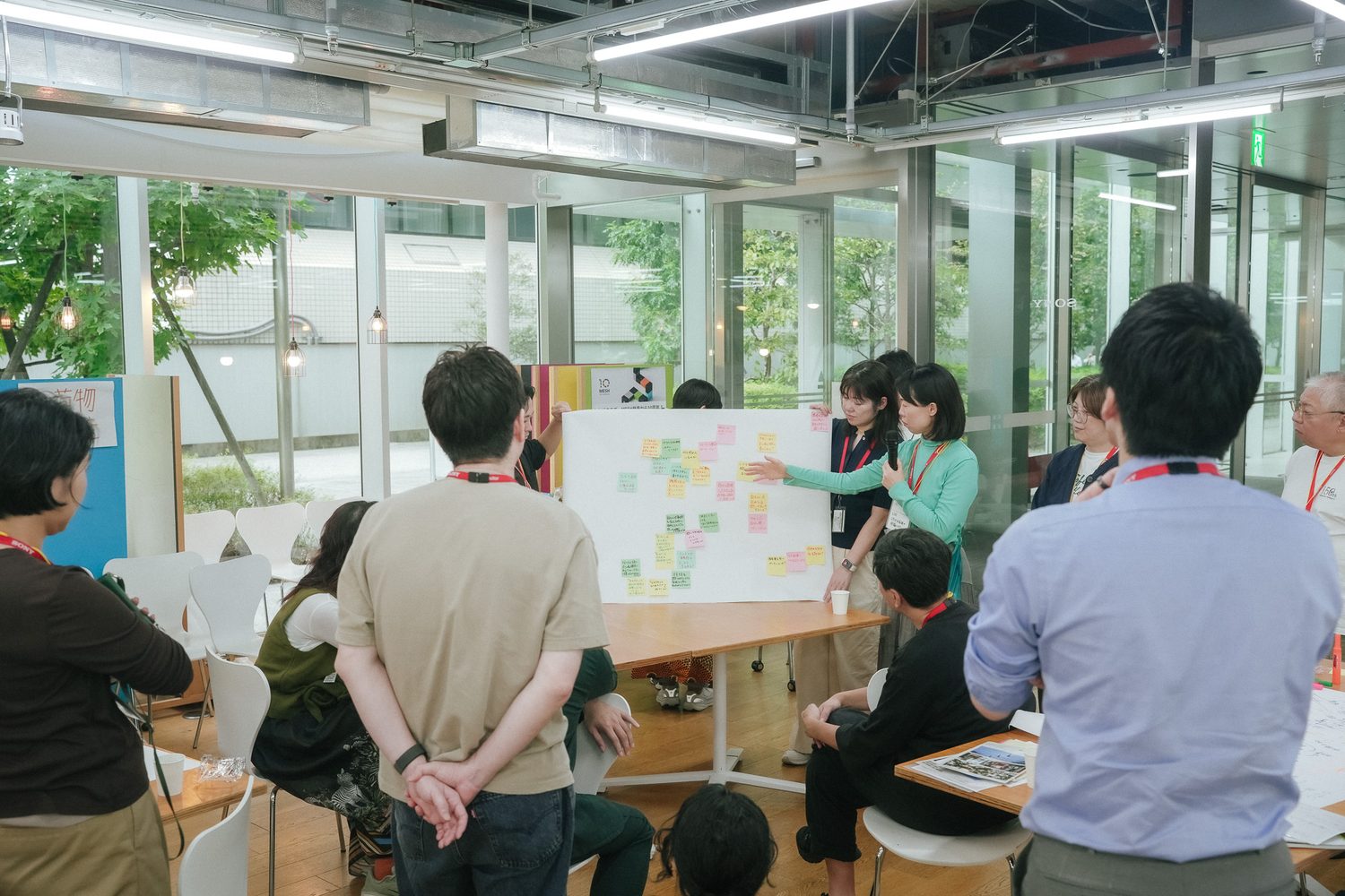 付箋の問いを貼った模造紙を囲み、話し合いを分かち合う参加者たち
